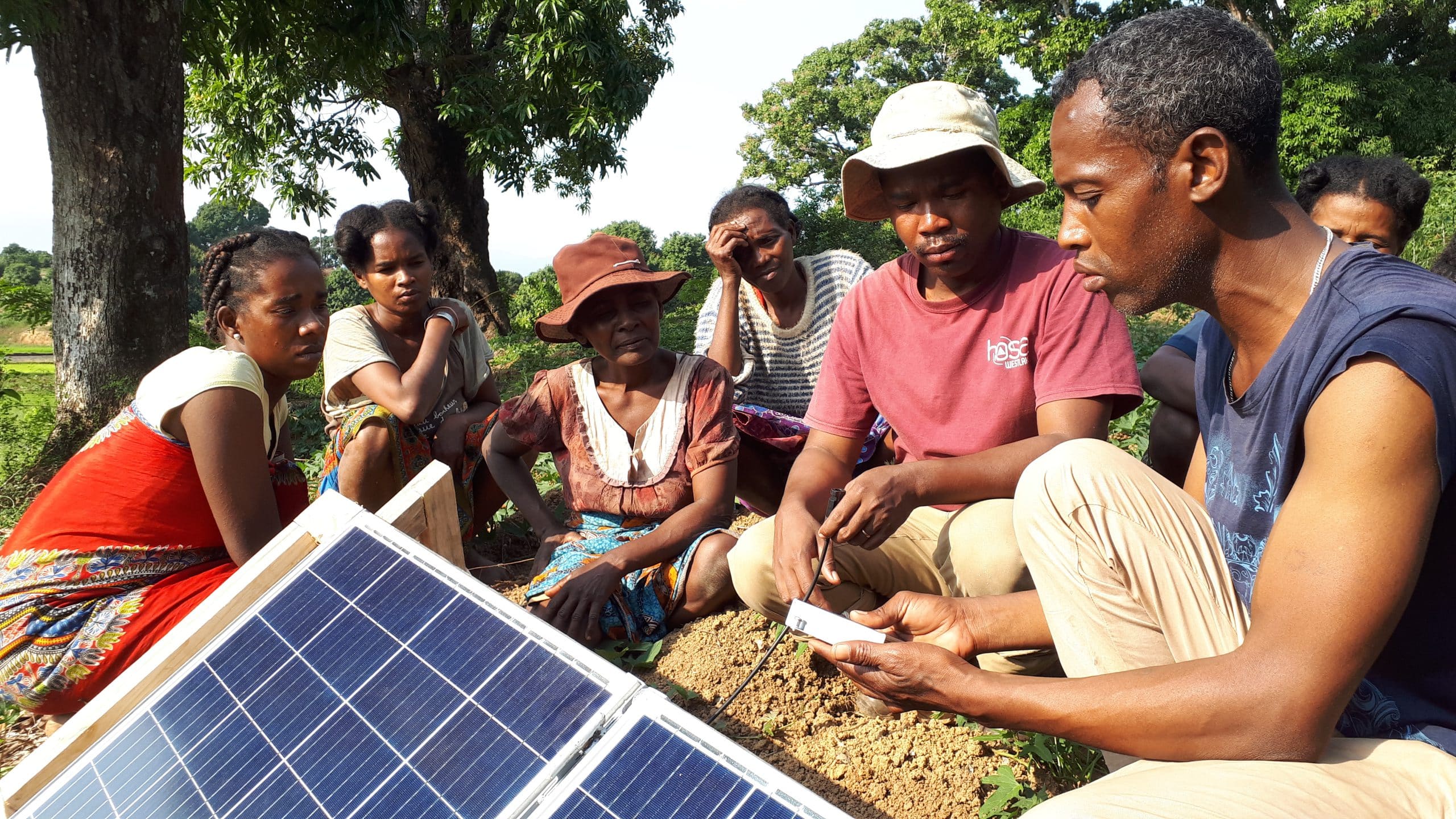 Demonstration of an app to a group of women next to solar panels