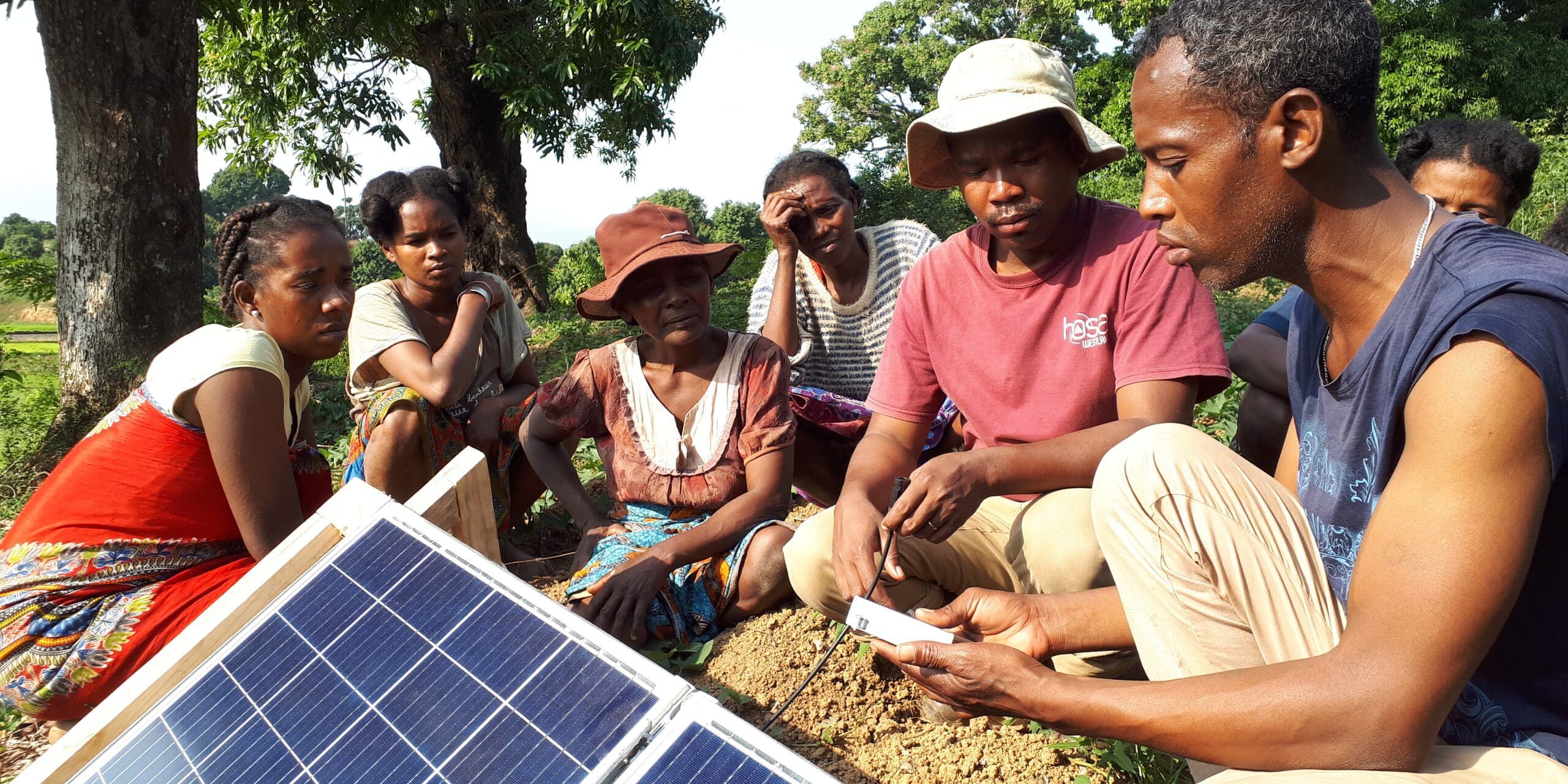Demonstration of an app to a group of women next to solar panels